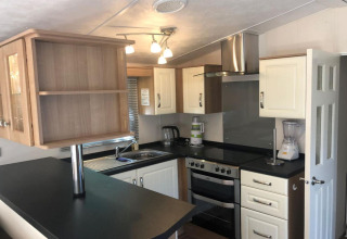 Cucina moderna con piani neri, mobili bianchi, fornello, frullatore e cappa in uno chalet in Belgio.