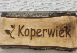 Pancarte en bois avec l'inscription 'Koperwiek' et motif de feuille, prise dans un chalet en Belgique.