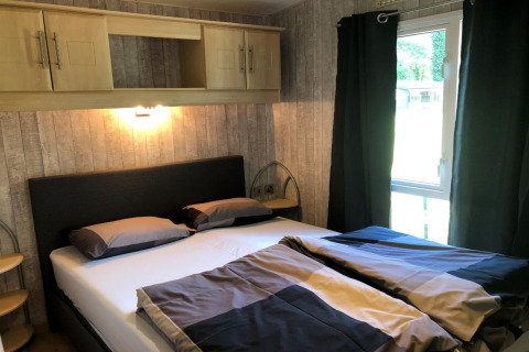Chambre avec lit double, mobilier moderne et fenêtre au Lodge Bosuil en Belgique, ambiance chaleureuse.