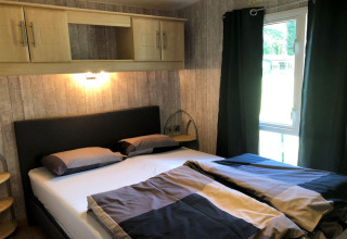 Soveværelse med dobbeltseng, moderne møbler og vindue på Lodge Bosuil i Belgien, hyggelig indretning.