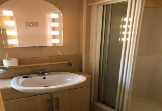 Salle de bain au lodge Bosuil en Belgique avec lavabo, miroir éclairé et cabine de douche.
