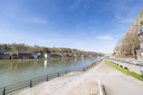 Vista sul fiume da una sistemazione glamping, con case pittoresche e colline sotto un cielo azzurro.