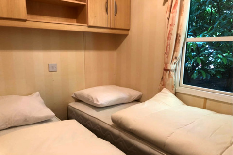 Twee eenpersoonsbedden in een compacte kamer van lodge Sijs in België, met raam en licht houtwerk.