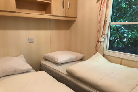 To enkeltsenge i et kompakt værelse på Sijs lodge i Belgien med vindue og lyst træmøblement.