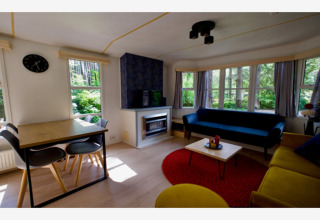 Coin salon lumineux dans le lodge Sijs en Belgique, avec canapés modernes, table à manger et fenêtres.