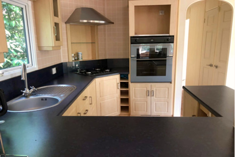 Cucina moderna con piani neri, lavello, forno e piano cottura al lodge Sijs in Belgio.