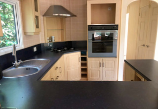 Moderne keuken met zwarte werkbladen, spoelbak, oven en kookvuur in Sijs-lodge in België.