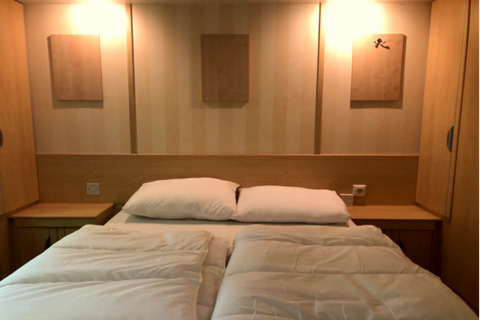 Camera moderna al lodge 'Sijs' in Belgio con letto matrimoniale, comodini e pannelli decorativi.