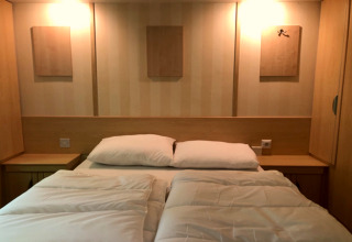 Camera moderna al lodge 'Sijs' in Belgio con letto matrimoniale, comodini e pannelli decorativi.