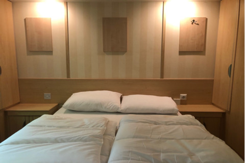 Camera moderna al lodge 'Sijs' in Belgio con letto matrimoniale, comodini e pannelli decorativi.