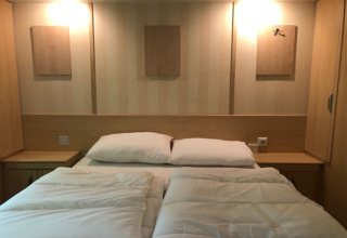 Camera moderna al lodge 'Sijs' in Belgio con letto matrimoniale, comodini e pannelli decorativi.