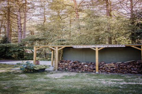 Foto di un deposito di legna presso un lodge, circondato da alberi e vegetazione in ambiente boschivo.