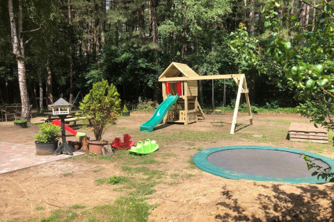 Area giochi in una sistemazione glamping con scivoli, altalene, trampolino e verde circostante.