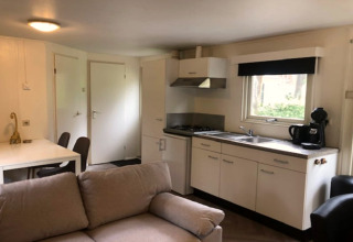 Gezellige leefruimte in lodge Ekster, België, met zetel, eettafel en compacte keukenhoek.