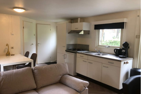 Accogliente soggiorno del lodge Ekster in Belgio, con divano, tavolo da pranzo e angolo cottura.