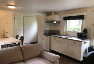 Lyst opholdsområde i Ekster-lodgen, Belgien, med sofa, spisebord og kompakt køkkenhjørne.