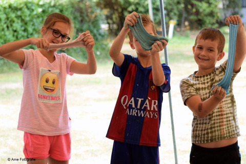 Trois enfants souriants s’amusent avec du slime fait maison devant le lodge «Ekster» en Belgique.