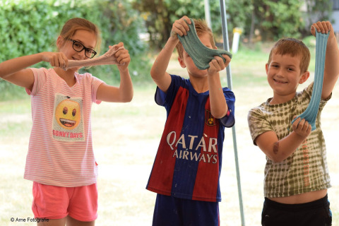 Trois enfants souriants s’amusent avec du slime fait maison devant le lodge «Ekster» en Belgique.