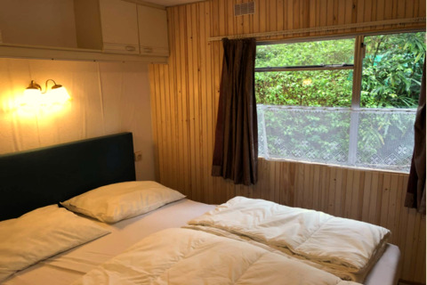 Accogliente camera da letto al chalet Specht in Belgio con letto matrimoniale e vista sul verde.