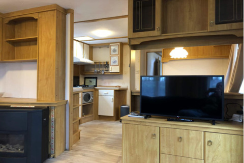 Espace salon du chalet Specht en Belgique, intérieur bois, TV, petite cuisine et ambiance chaleureuse.