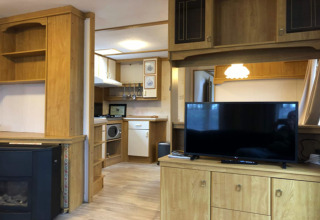 Espace salon du chalet Specht en Belgique, intérieur bois, TV, petite cuisine et ambiance chaleureuse.