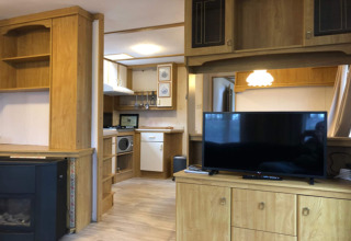 Espace salon du chalet Specht en Belgique, intérieur bois, TV, petite cuisine et ambiance chaleureuse.