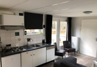 Cuisine et séjour modernes dans un lodge en Belgique, avec armoires blanches et vue sur la forêt.