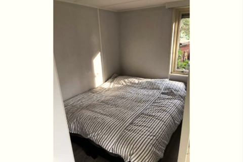 Piccola camera da letto al lodge 'Koolmees' in Belgio, con letto matrimoniale e finestra sul giardino.