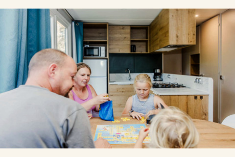 Een familie speelt een bordspel aan de eettafel in de moderne keuken van lodge Sparrowhawk in België.