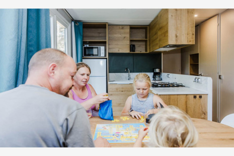 Eine Familie spielt ein Brettspiel am Esstisch in der modernen Küche der Lodge Sparrowhawk in Belgien.