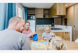 Une famille joue à un jeu de société à table dans la cuisine moderne du lodge Sparrowhawk, en Belgique.
