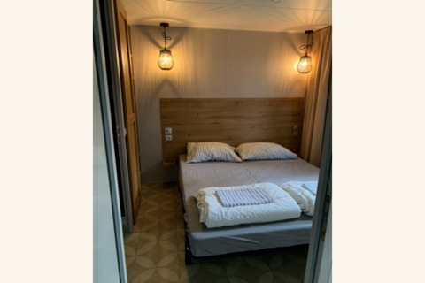 Gezellige slaapkamer met tweepersoonsbed, houten hoofdbord en sfeervolle lampen in lodge Sparrowhawk.