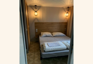 Gezellige slaapkamer met tweepersoonsbed, houten hoofdbord en sfeervolle lampen in lodge Sparrowhawk.