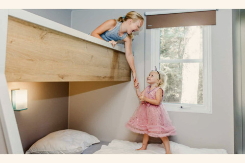 Twee kinderen spelen op een stapelbed in de Sparrowhawk-lodge in België, vrolijk hand in hand.