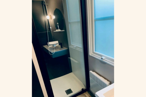 Moderne douche met glazen deur, ronde spiegel en matglas raam in het Sparrowhawk lodge in België.