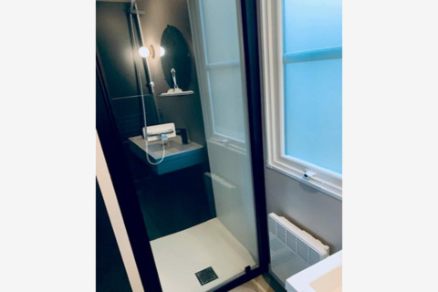 Moderne bruser med glasdør, sort panel og rund spejl på væggen i Sparrowhawk lodge i Belgien.