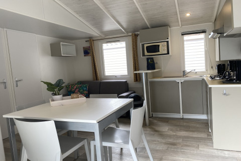 Interno luminoso di un lodge con cucina, tavolo da pranzo e divano presso Verblijfpark Breebos 2 in Belgio.