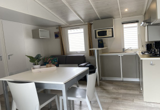 Interno luminoso di un lodge con cucina, tavolo da pranzo e divano presso Verblijfpark Breebos 2 in Belgio.
