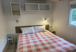 Camera da letto al Verblijfpark Breebos 2 in Belgio con copriletto a quadretti, mensole e finestra.