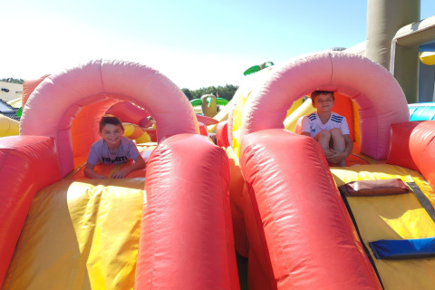 Twee kinderen spelen op een kleurrijk springkussen buiten op een zonnige dag bij een lodge.
