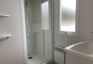 Bagno moderno con box doccia, lavandino e finestra al lodge Verblijfpark Breebos 2 in Belgio.