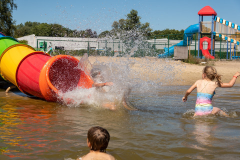 Bambini che giocano e schizzano nell’acqua vicino a uno scivolo colorato in un lodge.