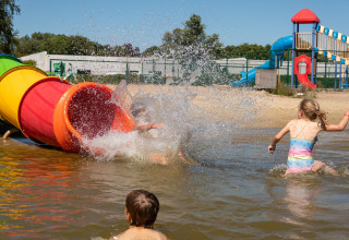 Kinderen spelen in het water bij een kleurrijke glijbaan op de speeltuin van een lodge.