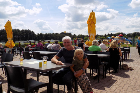 Un uomo e un bambino siedono a un tavolo esterno al Verblijfpark Breebos 2 lodge in Belgio.
