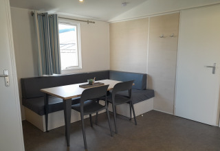 Moderne eethoek met hoekbank, tafel en vier stoelen in Verblijfpark Breebos 3, België.