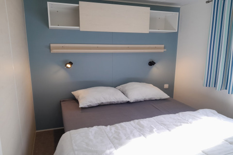 Moderne slaapkamer in Verblijfpark Breebos 3, België met tweepersoonsbed, wandlampen en plank.