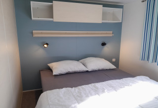 Camera moderna al Verblijfpark Breebos 3 in Belgio con letto matrimoniale, luci a muro e mensola.