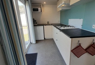 Moderne, compacte keuken in een lodge op Verblijfpark Breebos 3, België, met fornuis en mini-koelkast.