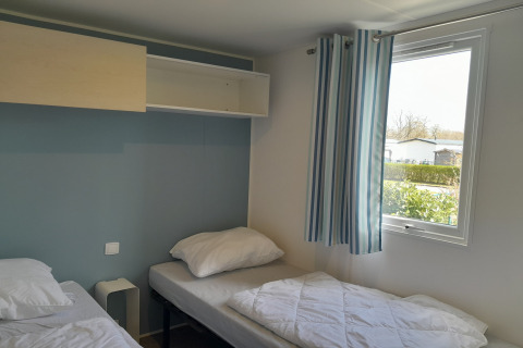 Lichte kamer in Verblijfpark Breebos 3 in België met twee eenpersoonsbedden en gestreepte gordijnen.