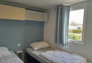 Lichte kamer in Verblijfpark Breebos 3 in België met twee eenpersoonsbedden en gestreepte gordijnen.